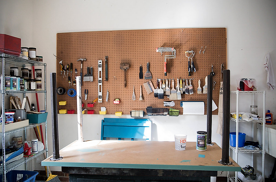 garage with tools organized on brown board hanging on wall with other tools on metal shelves